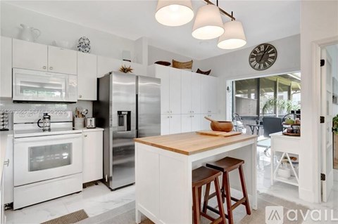 A kitchen with white cabinets and a wooden island.