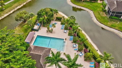 An aerial view of a pool surrounded by palm trees and lounge chairs.