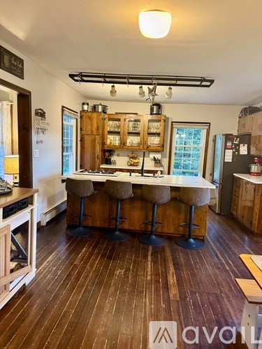 A kitchen with wooden floors and a large island with bar stools.