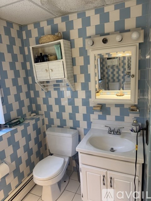 A bathroom with a toilet, sink, and mirror.
