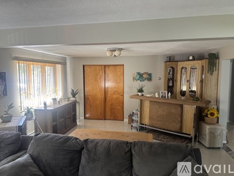 A living room with a grey couch and wooden furniture.