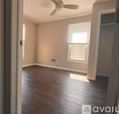 A room with a ceiling fan and wooden flooring.