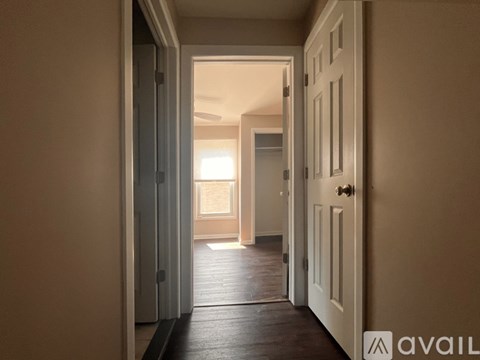 A hallway with a door on the right and a window in the distance.