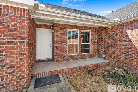 A small brick house with a white door and a window with a white frame.