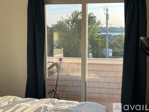 A bedroom with a large window overlooking a street.