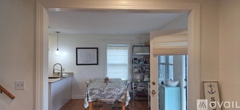 A kitchen area with a sink and a dining table with chairs.