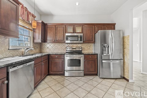 A kitchen with wooden cabinets and a stainless steel refrigerator.