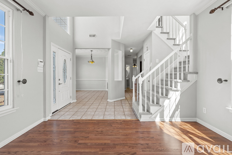 A spacious hallway with a staircase and a chandelier.