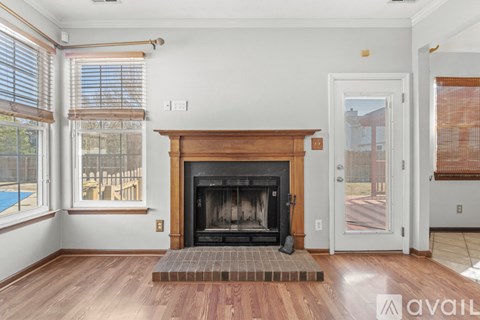 A living room with a fireplace and a pool outside the window.