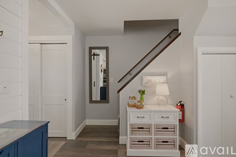 A hallway with a staircase and a white cabinet with drawers.