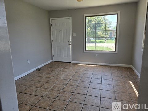 A room with a tiled floor and a window showing a view of trees.