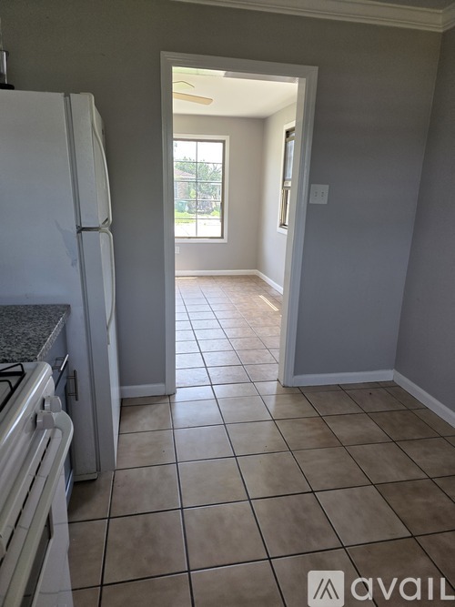 A kitchen with a white fridge and tiled floor.