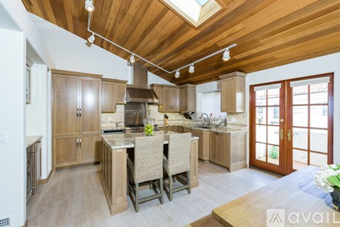 A kitchen with wooden cabinets and a large island with a sink.