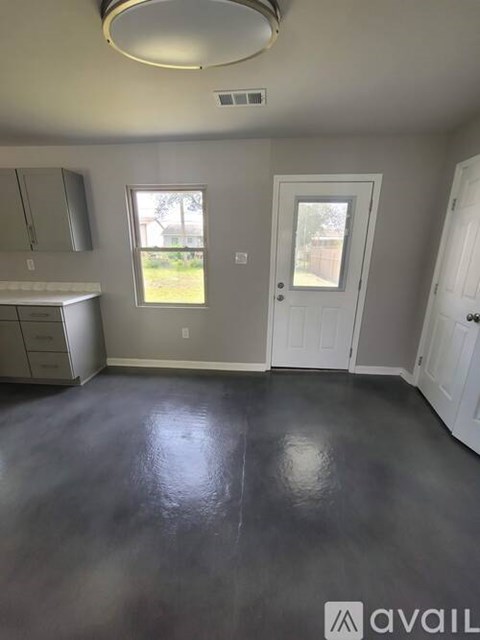 A room with grey flooring and a white door.