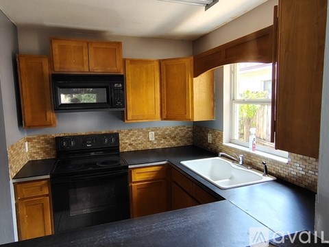A kitchen with black appliances and wooden cabinets.