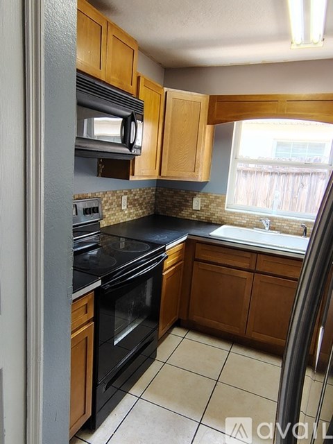 A kitchen with wooden cabinets and black appliances.