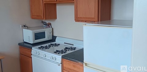 A white microwave oven is on a countertop above a white gas stove.