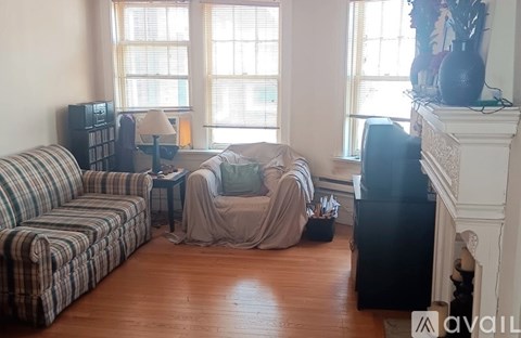 A living room with a striped couch, a chair with a blanket, and a fireplace.