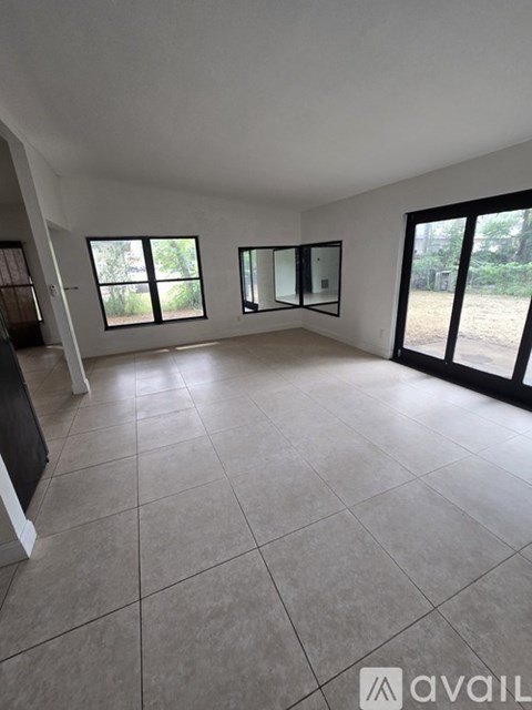 A spacious room with large windows and tiled flooring.