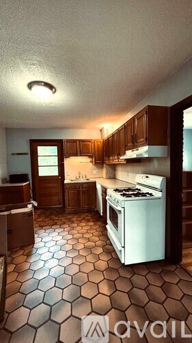 A kitchen with a white stove top oven and wooden cabinets.