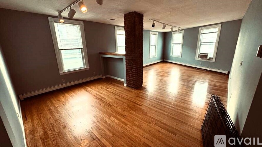 A room with wooden floors and a brick pillar.
