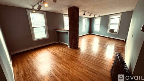 A room with wooden floors and a brick pillar.