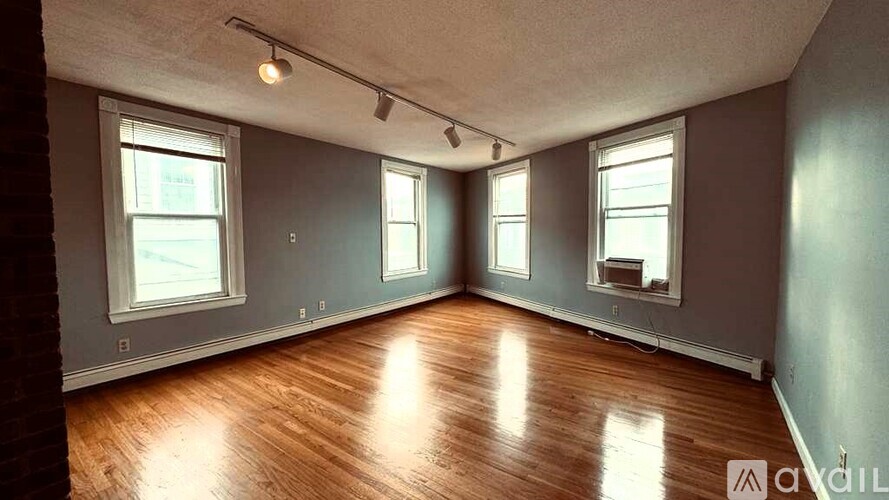 A room with wooden floors and three windows.