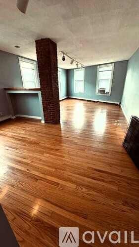 A room with wooden floors and a brick pillar.