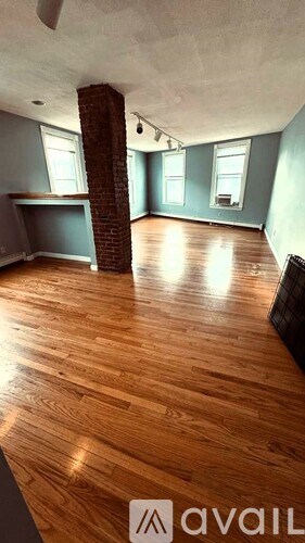A room with wooden floors and a brick pillar.