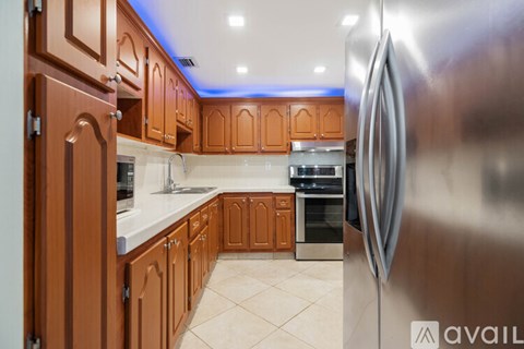 A kitchen with wooden cabinets and a stainless steel refrigerator.