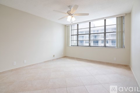 A room with a ceiling fan and a window with a view of a building outside.