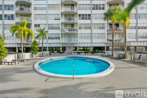 A large white apartment building with a blue pool in the courtyard.