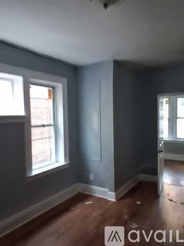 A room with grey walls and wooden floors is available for rent.