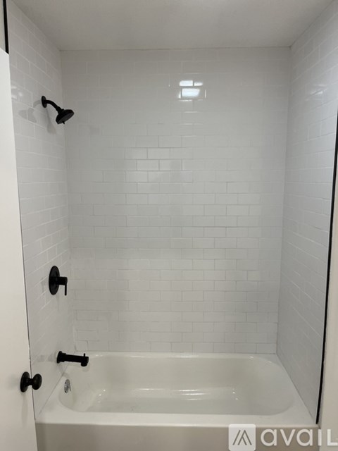 A white tiled bathroom with a white bathtub and a white shower.