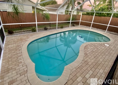 A small kid is playing in a kidney shaped pool.