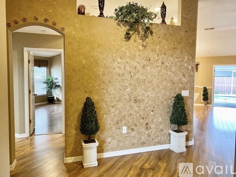 A room with a gold wallpaper and two potted trees.