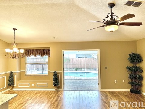 A living room with a ceiling fan and a pool in the backyard.