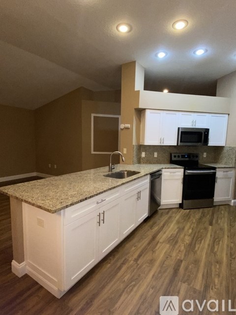 A kitchen with white cabinets and a granite countertop.