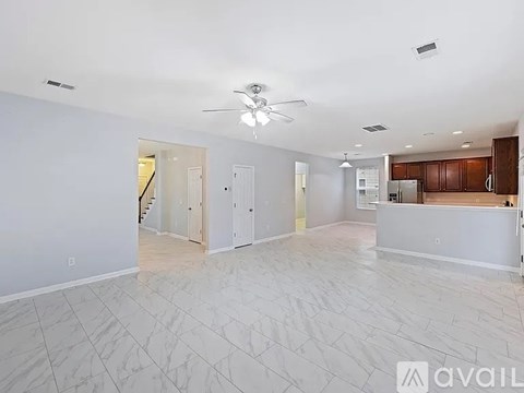 A spacious living room with a ceiling fan and lighting fixtures.