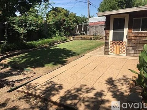 A wooden deck in a backyard with a house and trees in the background.