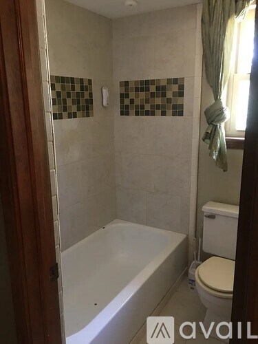 A bathroom with a toilet, tub, and tiled walls.