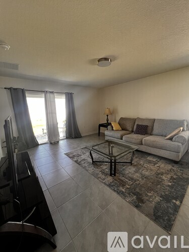 A living room with a grey couch and a black television.
