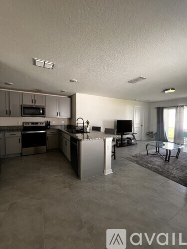 A kitchen with a refrigerator, microwave, oven, and sink.