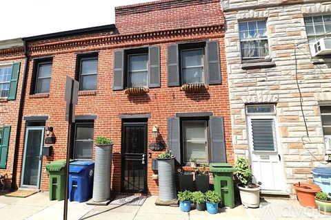A row of houses with green and blue bins in front.