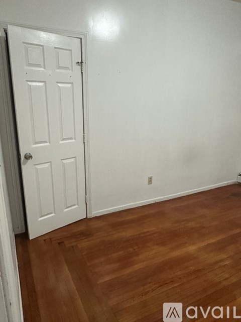 A white door is in a room with wooden floors.