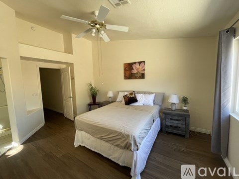 A bedroom with a bed, nightstands, and a ceiling fan.