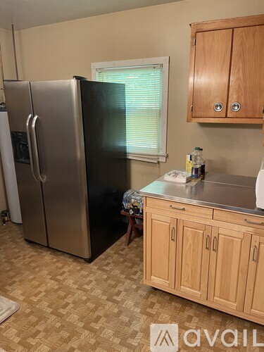 A kitchen with a stainless steel refrigerator and wooden cabinets.