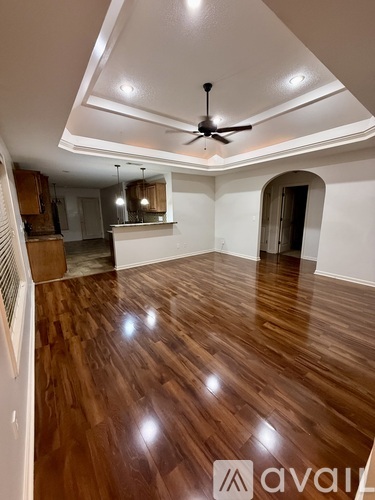 A spacious room with wooden flooring and a ceiling fan.