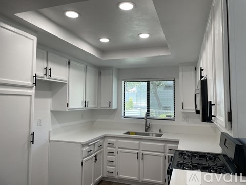 A modern kitchen with white cabinets and a window.