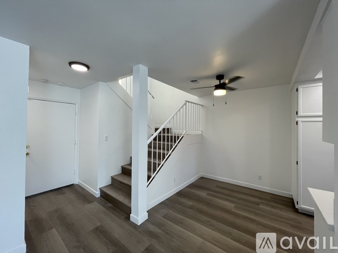 A spacious room with a staircase and a ceiling fan.
